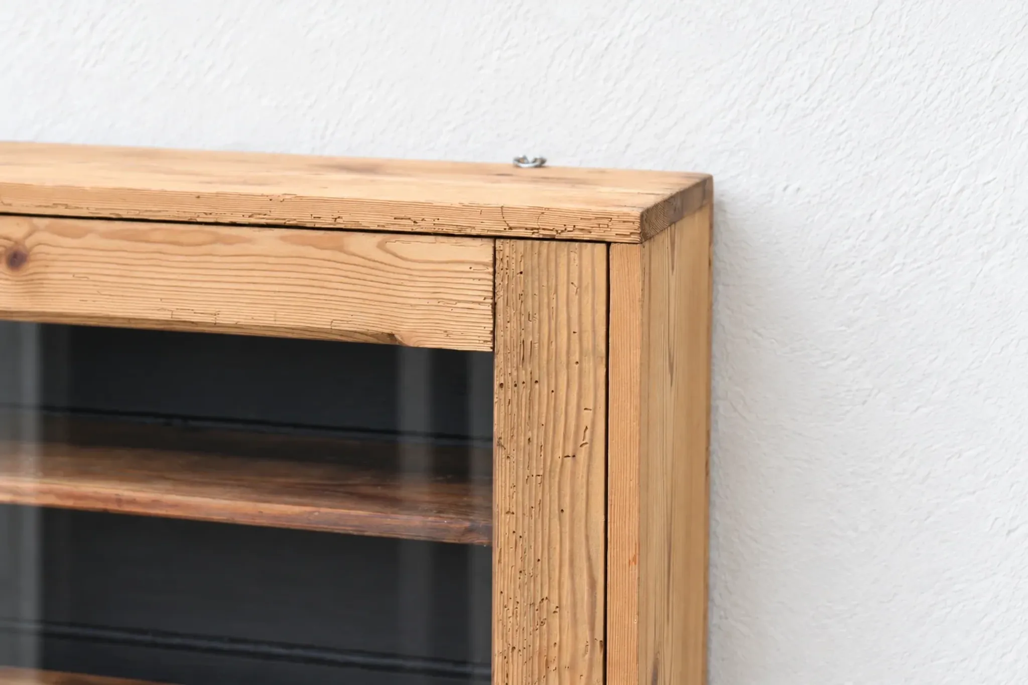 Antique wall display cabinet in natural wood and black – small glass-fronted collector's piece.
