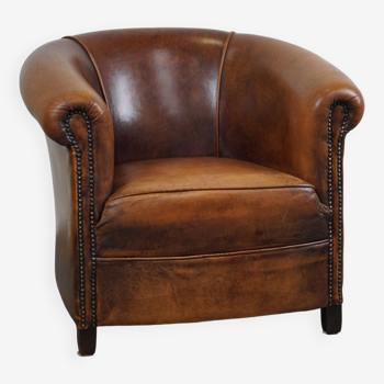 A sheep leather club armchair in good condition, modest in size