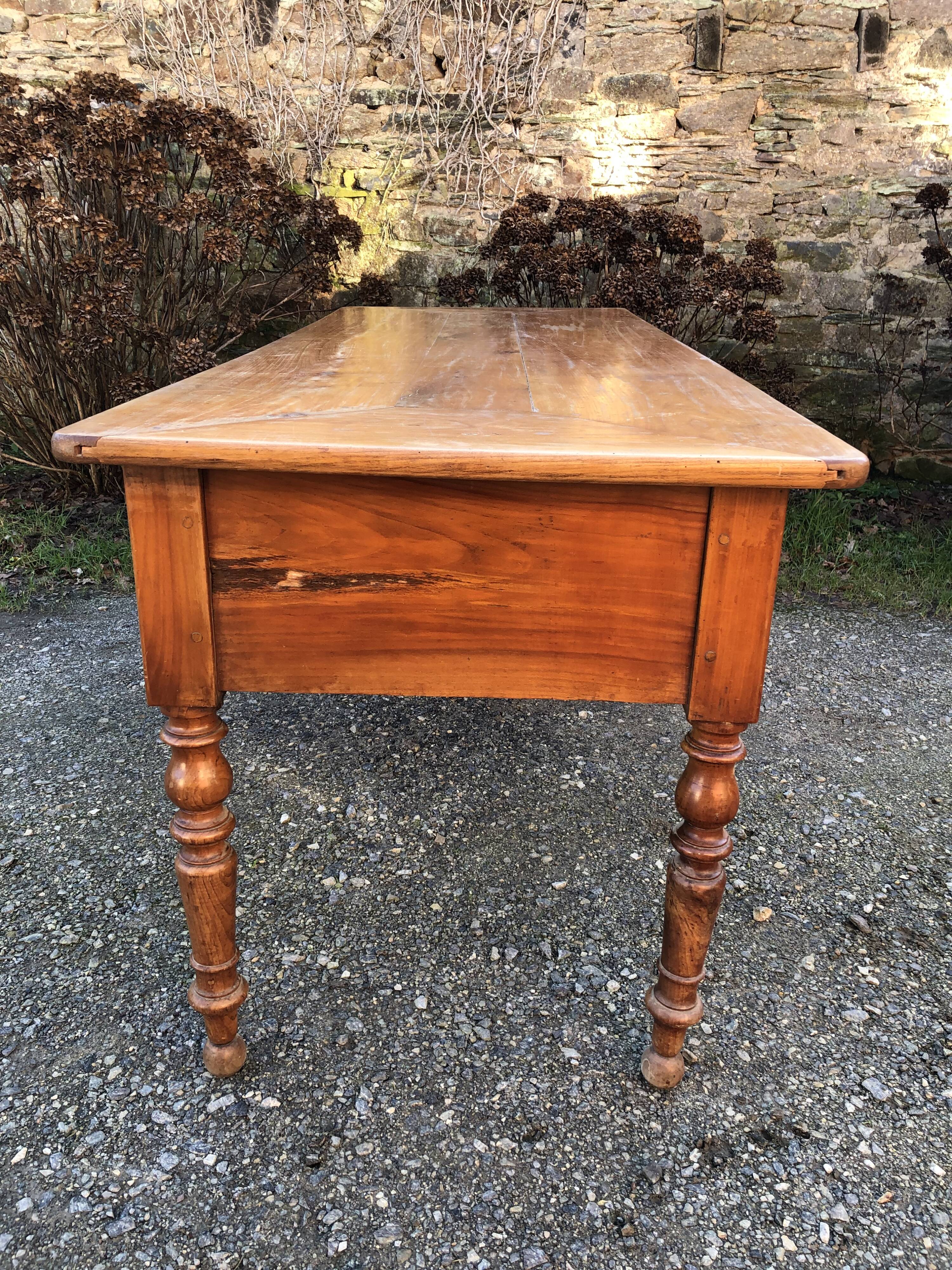 Antique cherry farmhouse table with turned legs and 2 drawers.