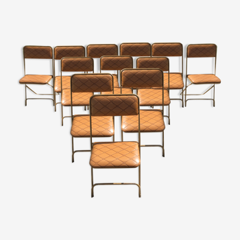 Set de 12 chaises vintage pliantes en skaï assises et dossiers matelassés à piètement tubulaire doré