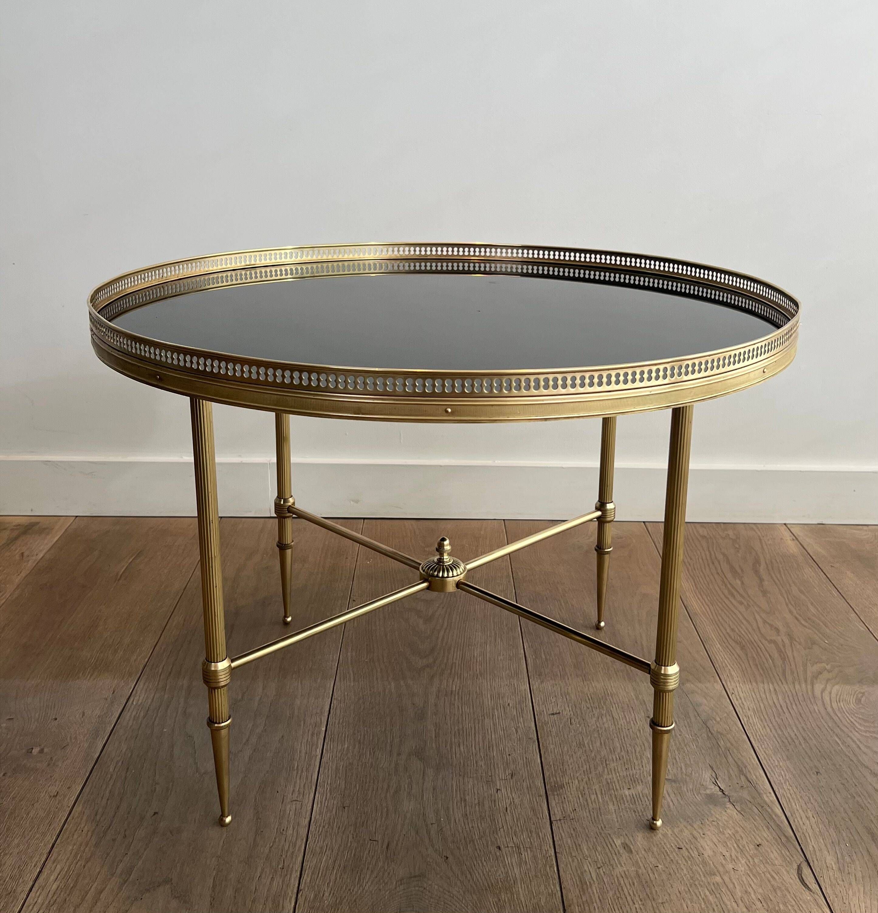 Round coffee table in brass with a black lacquered glass top from Maison Jansen.