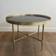 Round coffee table in brass with a black lacquered glass top from Maison Jansen.