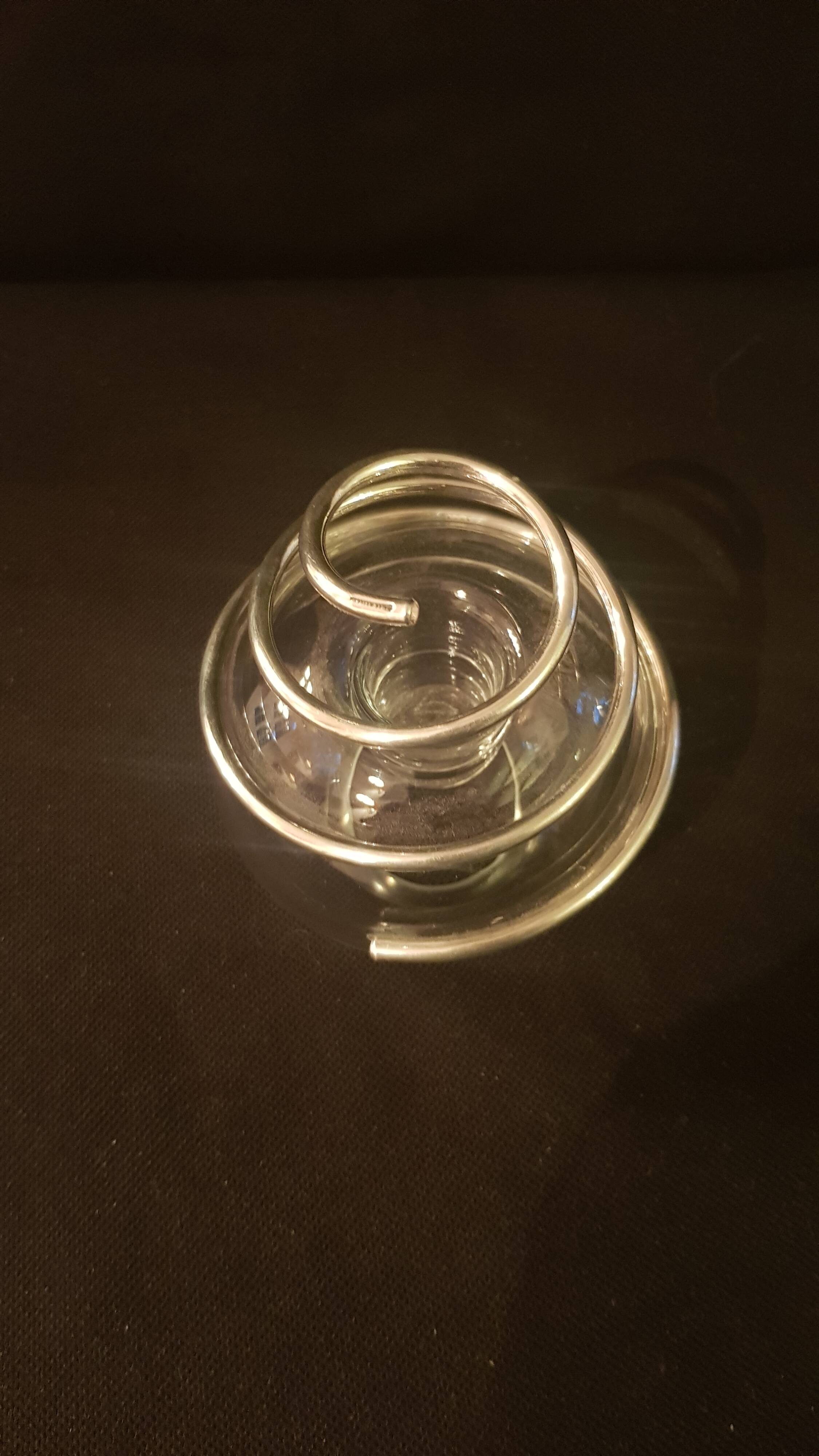 Round glass candle holder with silver-plated metal spiral.