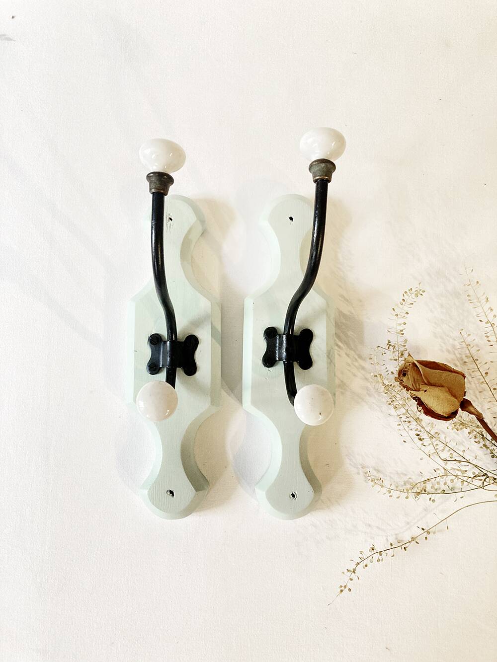 Antique metal and porcelain coat hooks, painted wooden support