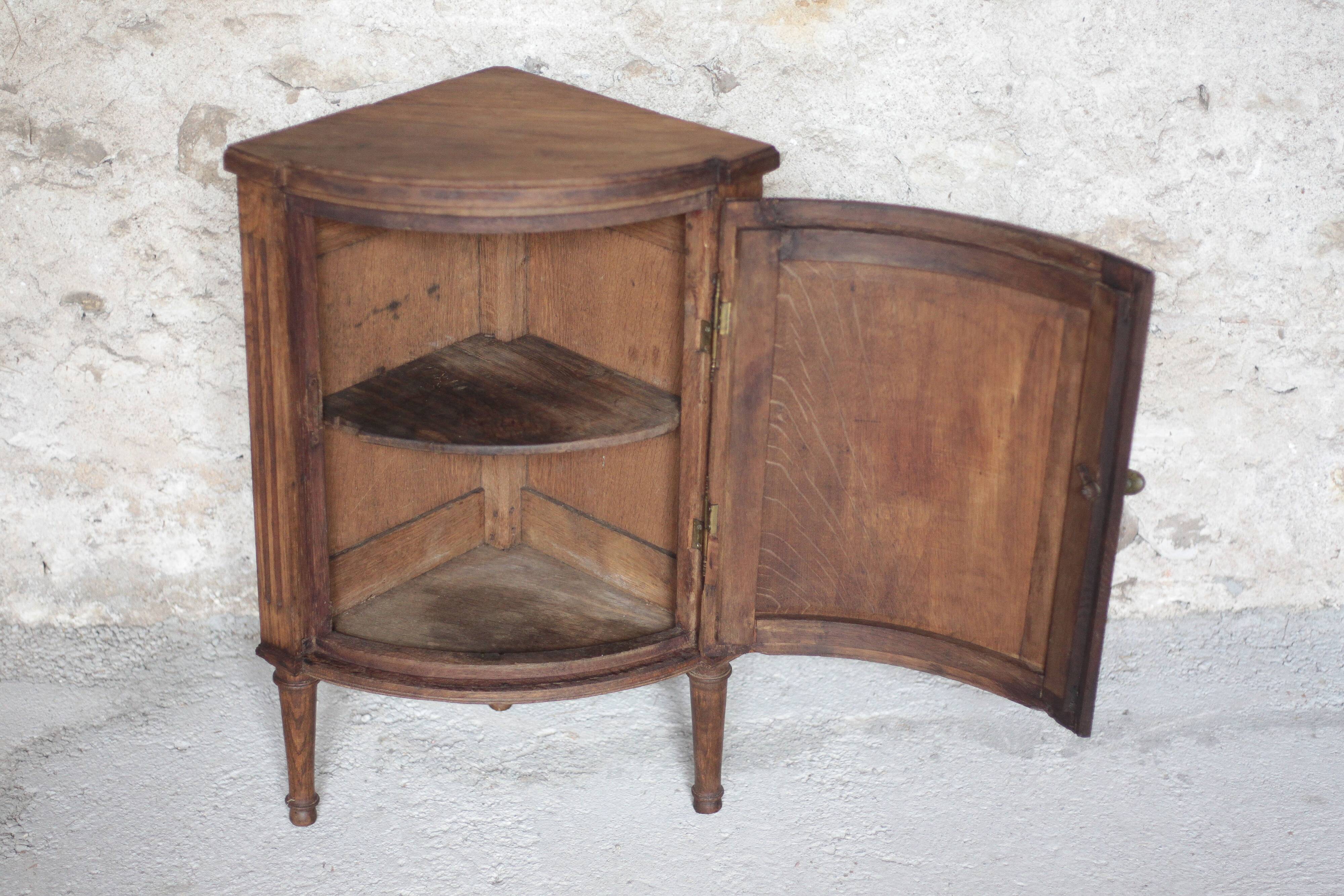 Antique wooden corner cabinet with a curved door.