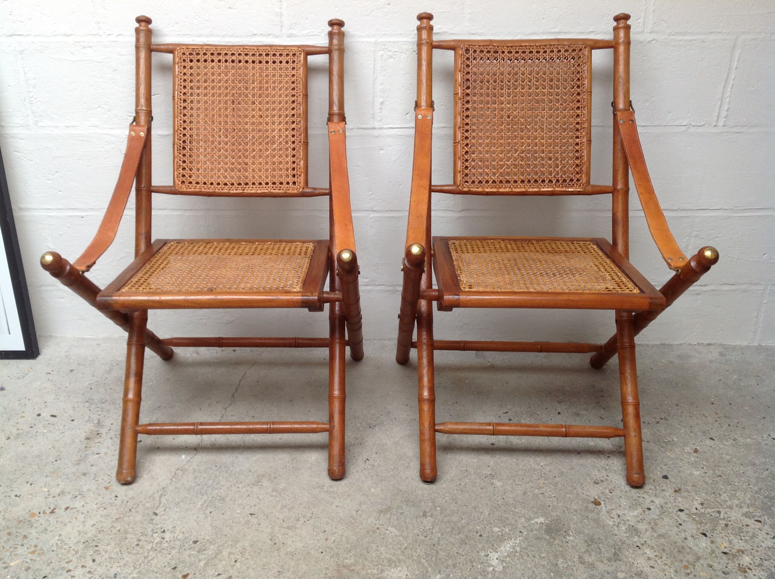 Pair of folding chairs in bamboo and caning, leather and brass