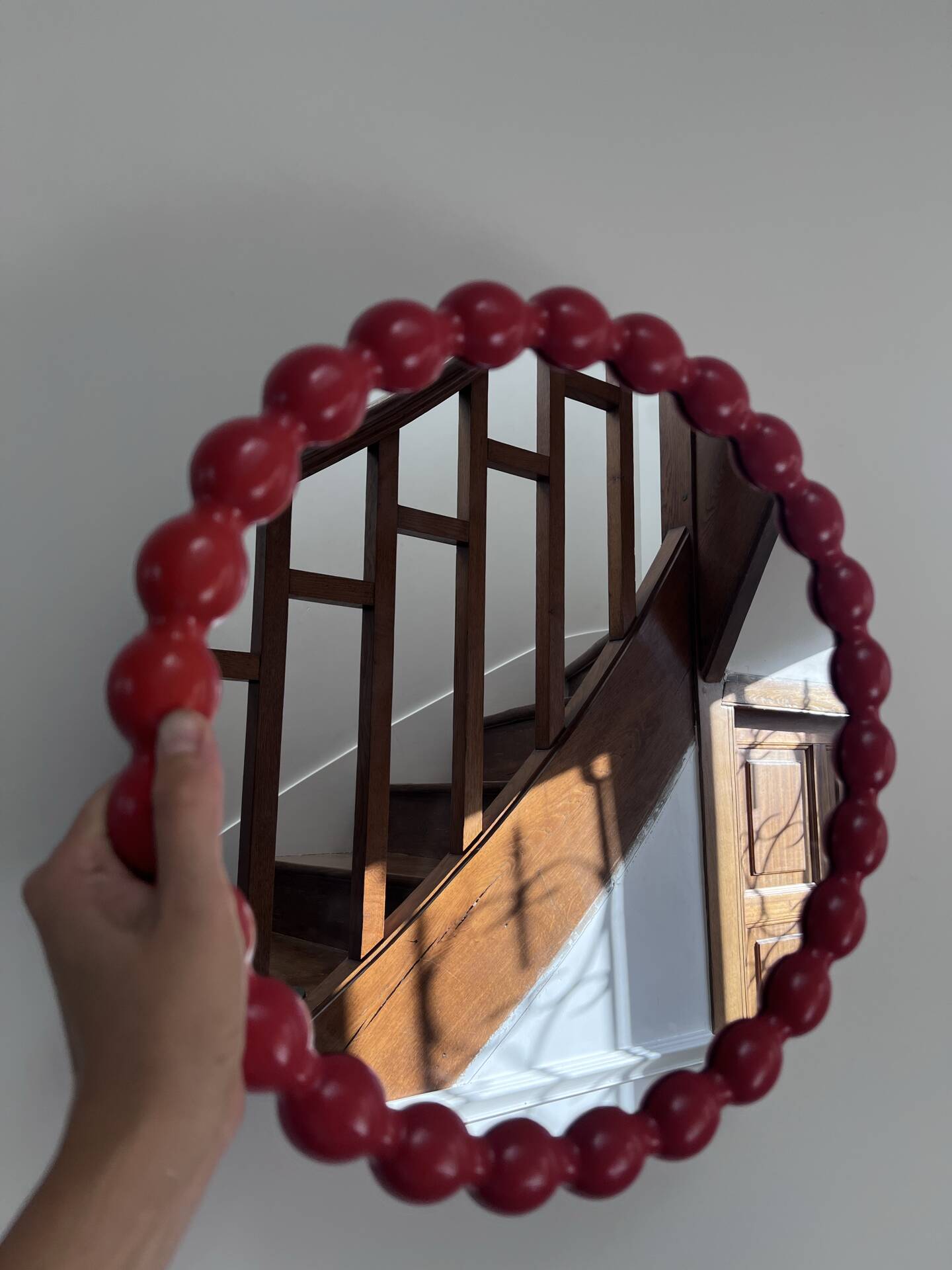 Round wall mirror with red beads in vintage retro design style.