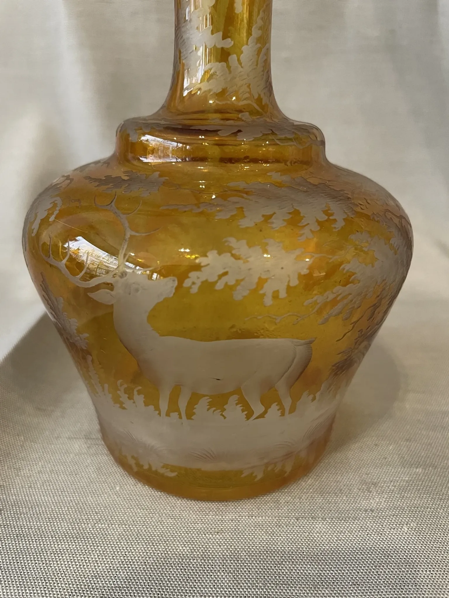 Amber bohemian glass liqueur carafe decorated with a stag in the forest.