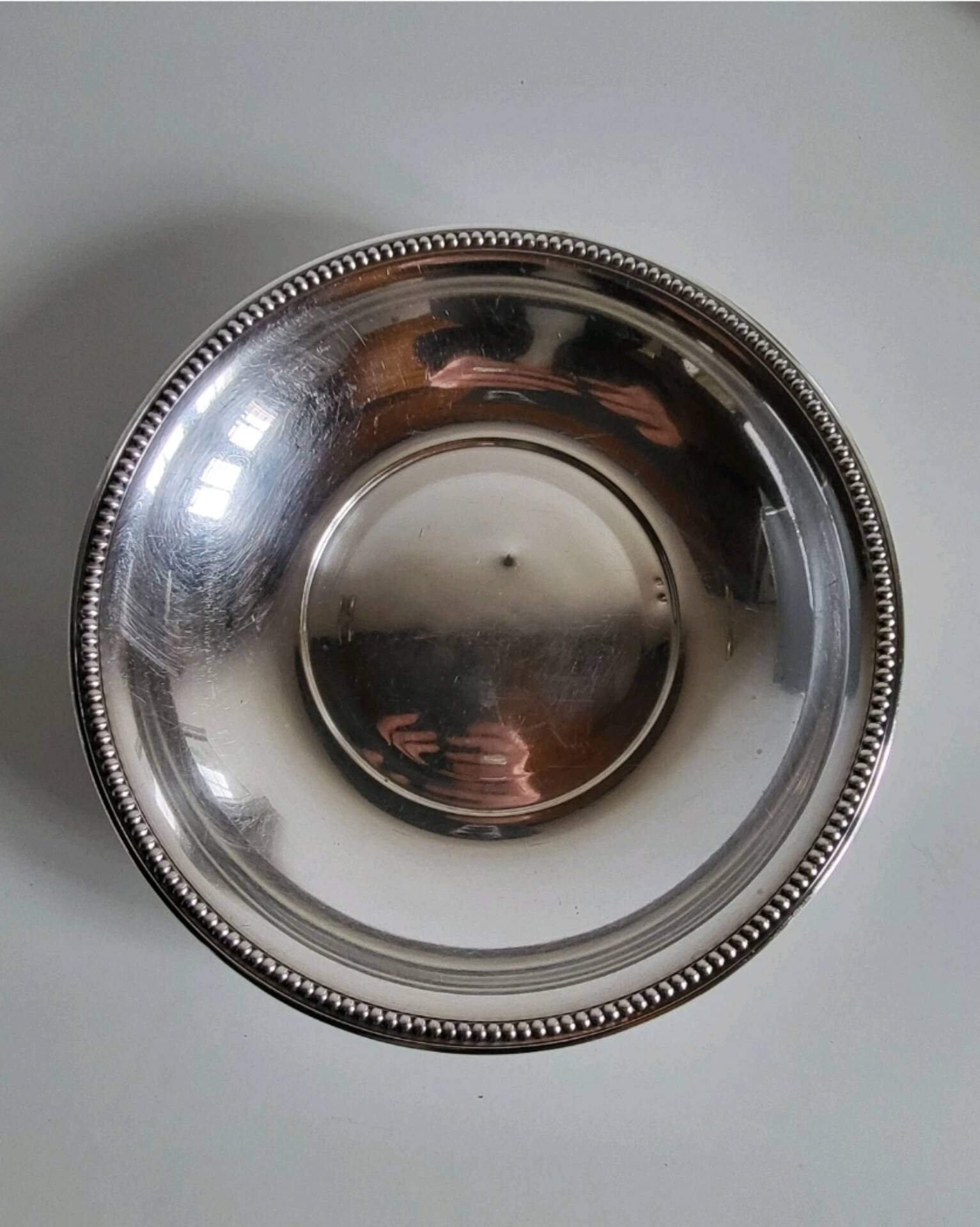 Shallow round metal plate with pearl row decoration.