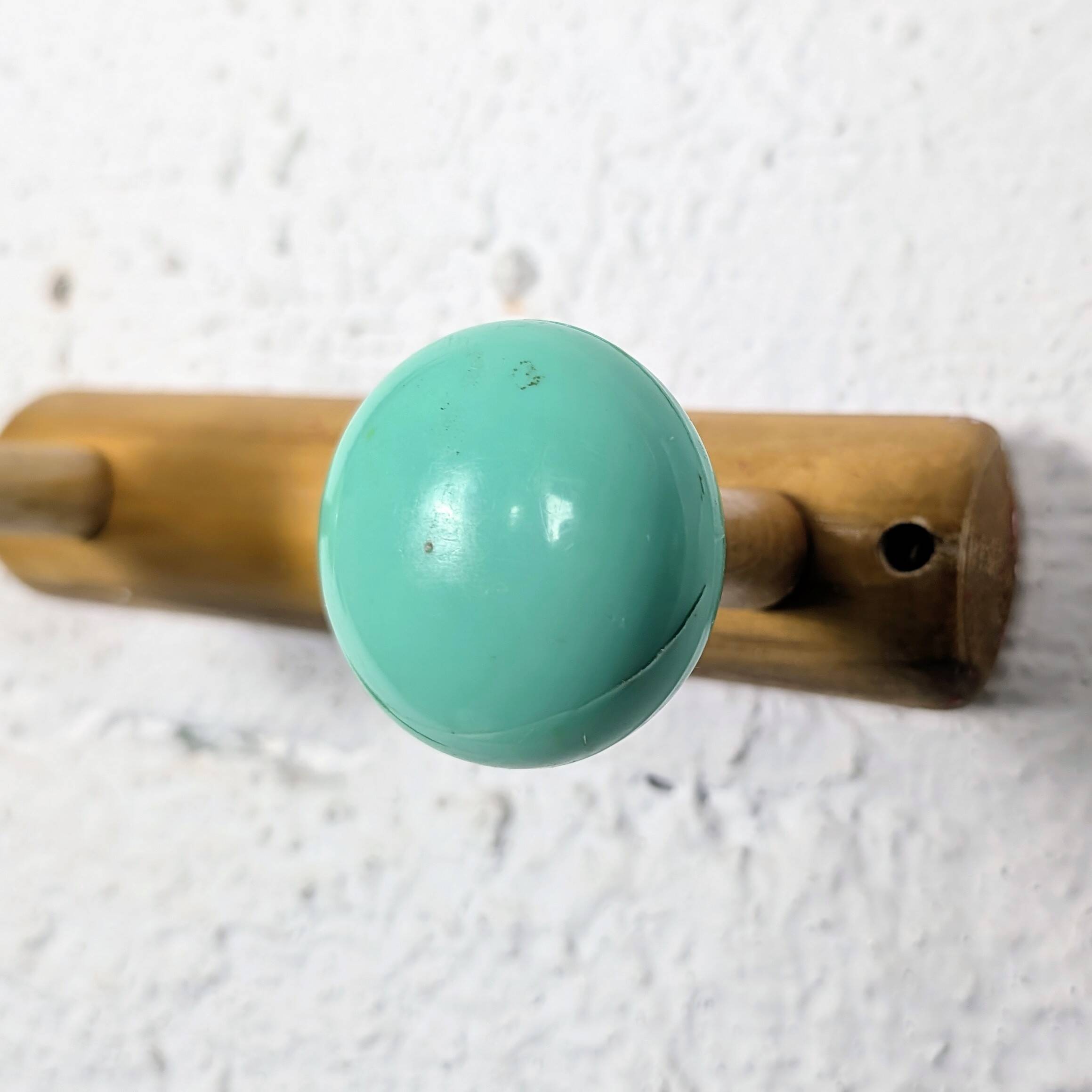Vintage wall coat rack with 2 yellow and green balls.