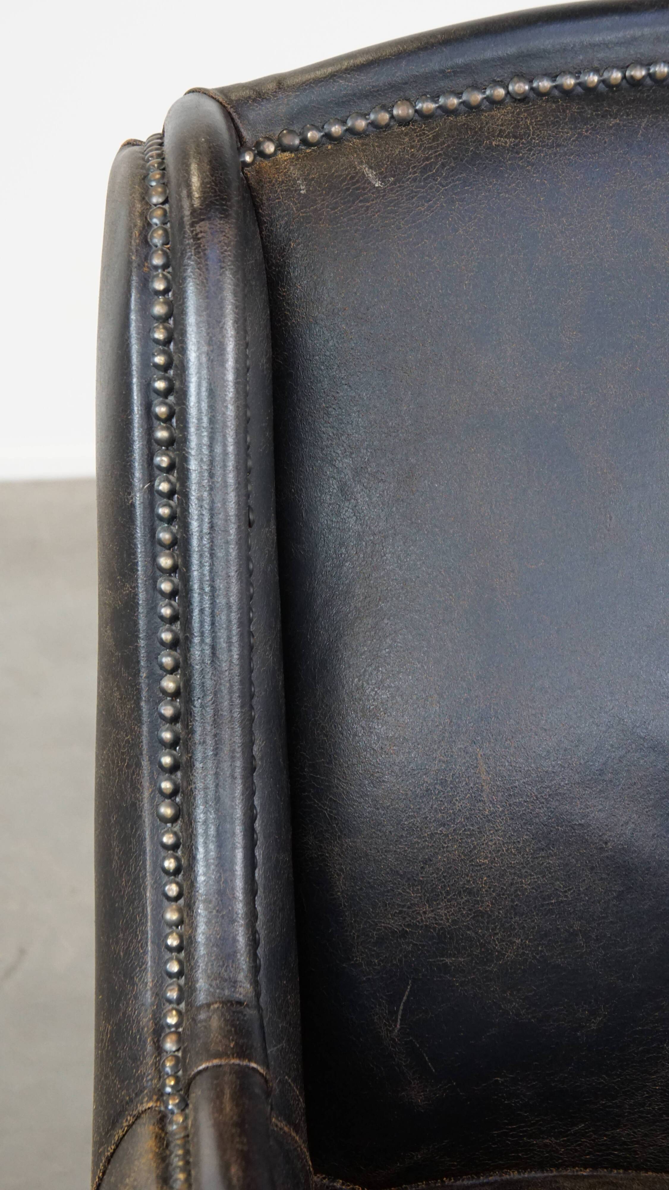 Black cow leather armchair in industrial style finished with decorative nails