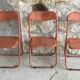 Trio of orange metal folding chairs - vintage