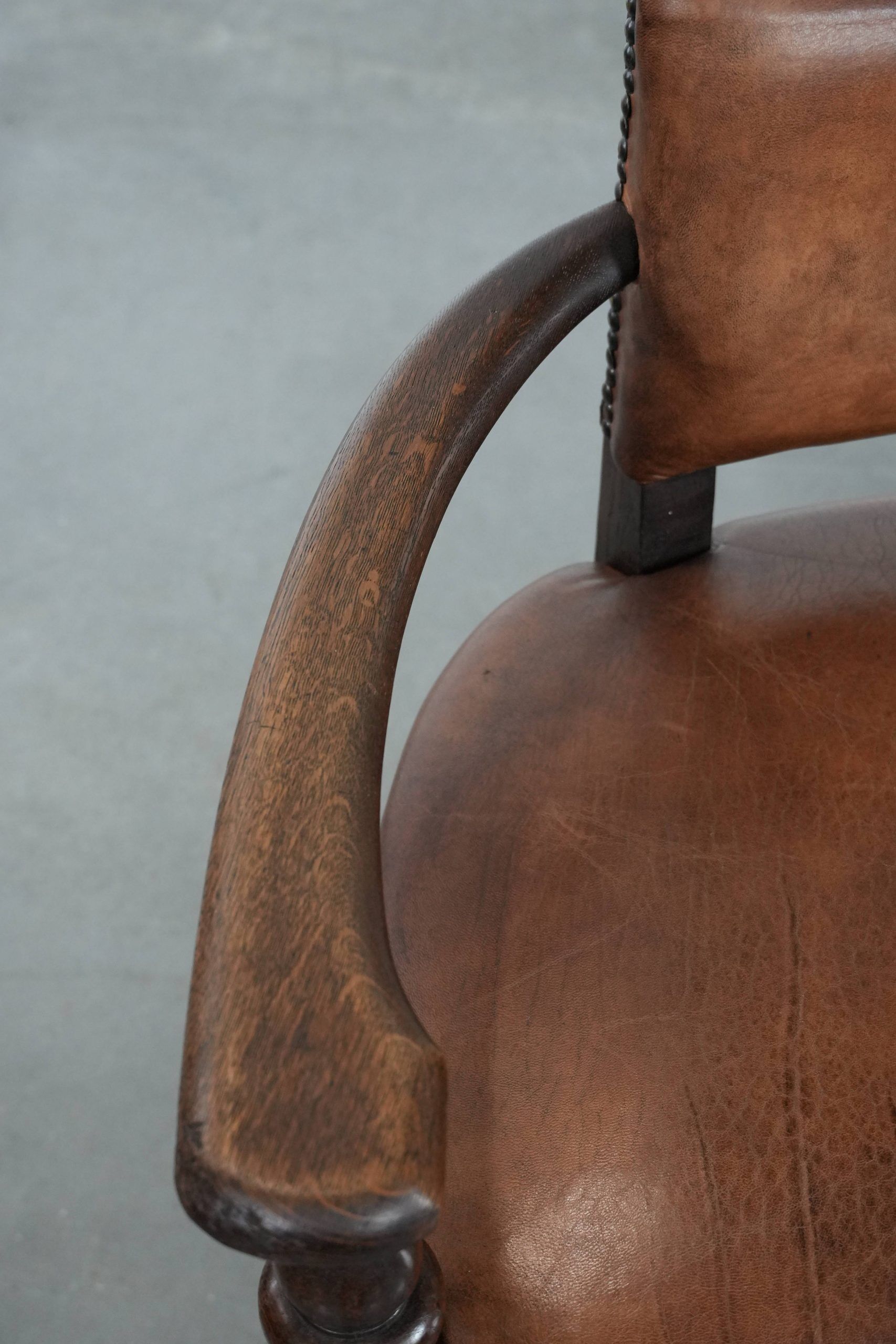 Elegant antique sheepskin leather desk chair with a heavy wooden frame