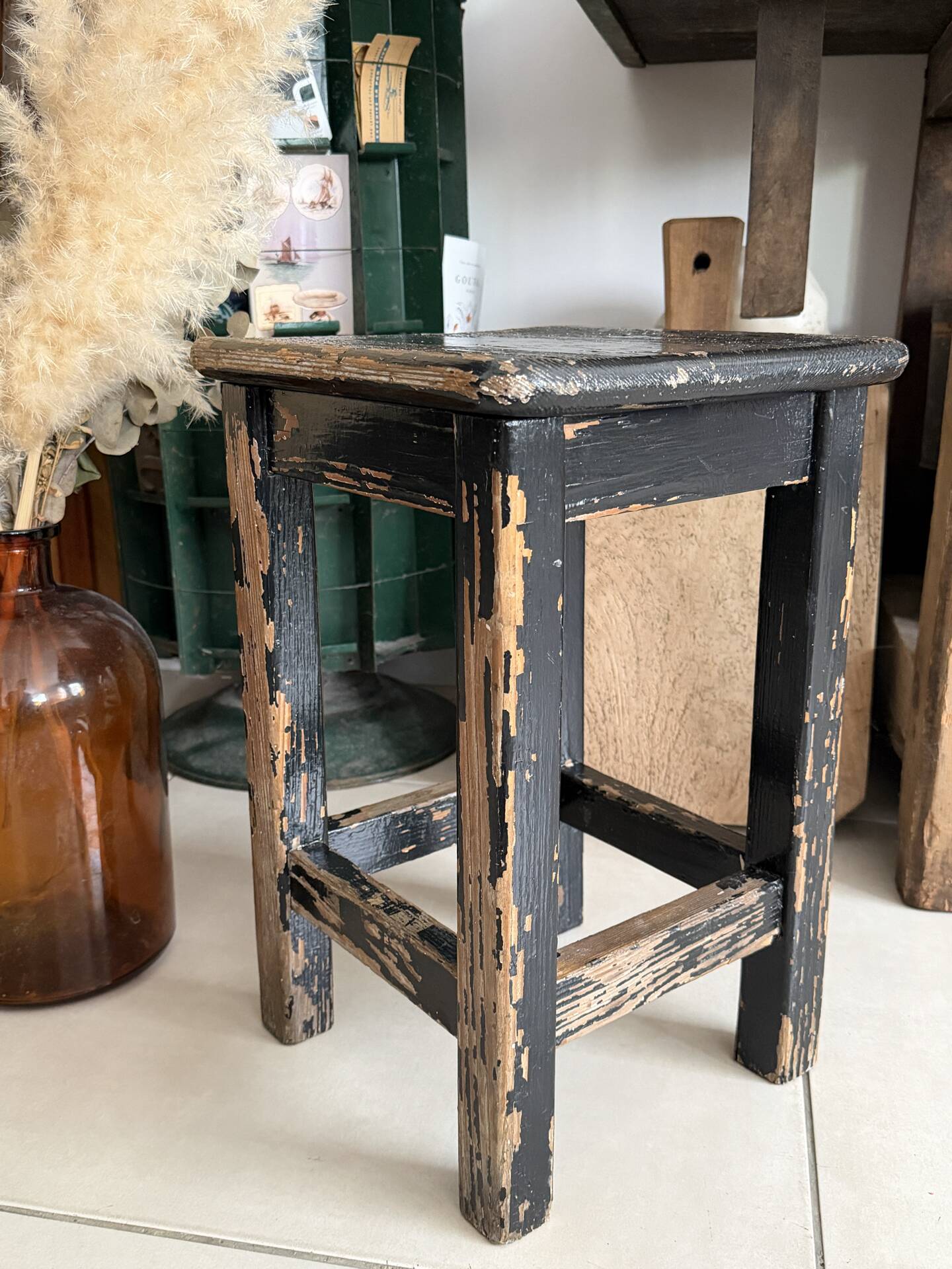 Solid wood stool with a worn black patina.
