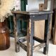 Solid wood stool with a worn black patina.