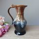 Vintage 1960s brown and blue flame-patterned stoneware wine jug carafe.