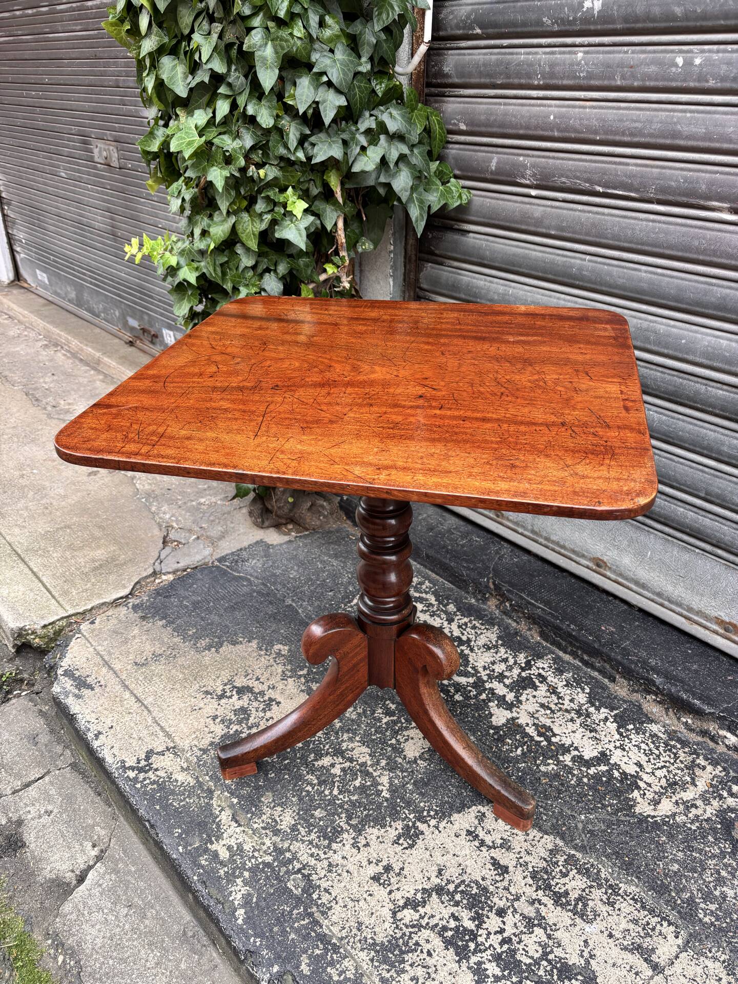 19th-century solid mahogany table with a tilting top and brass mechanism.