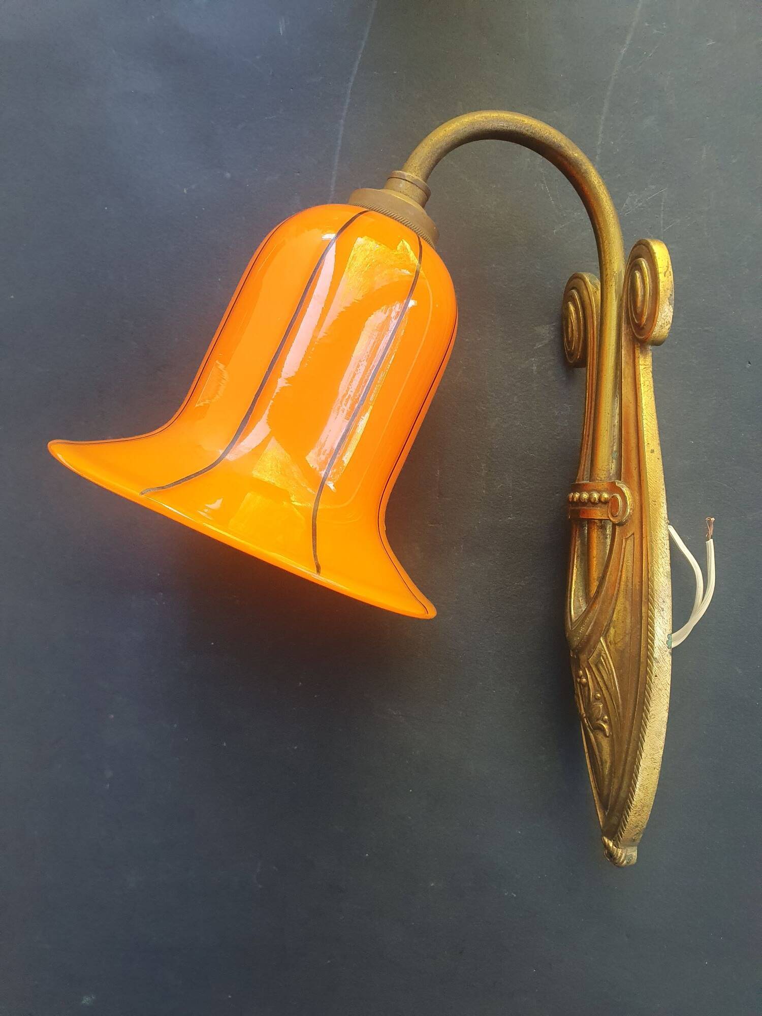 Art Deco wall light in brass with an orange globe.