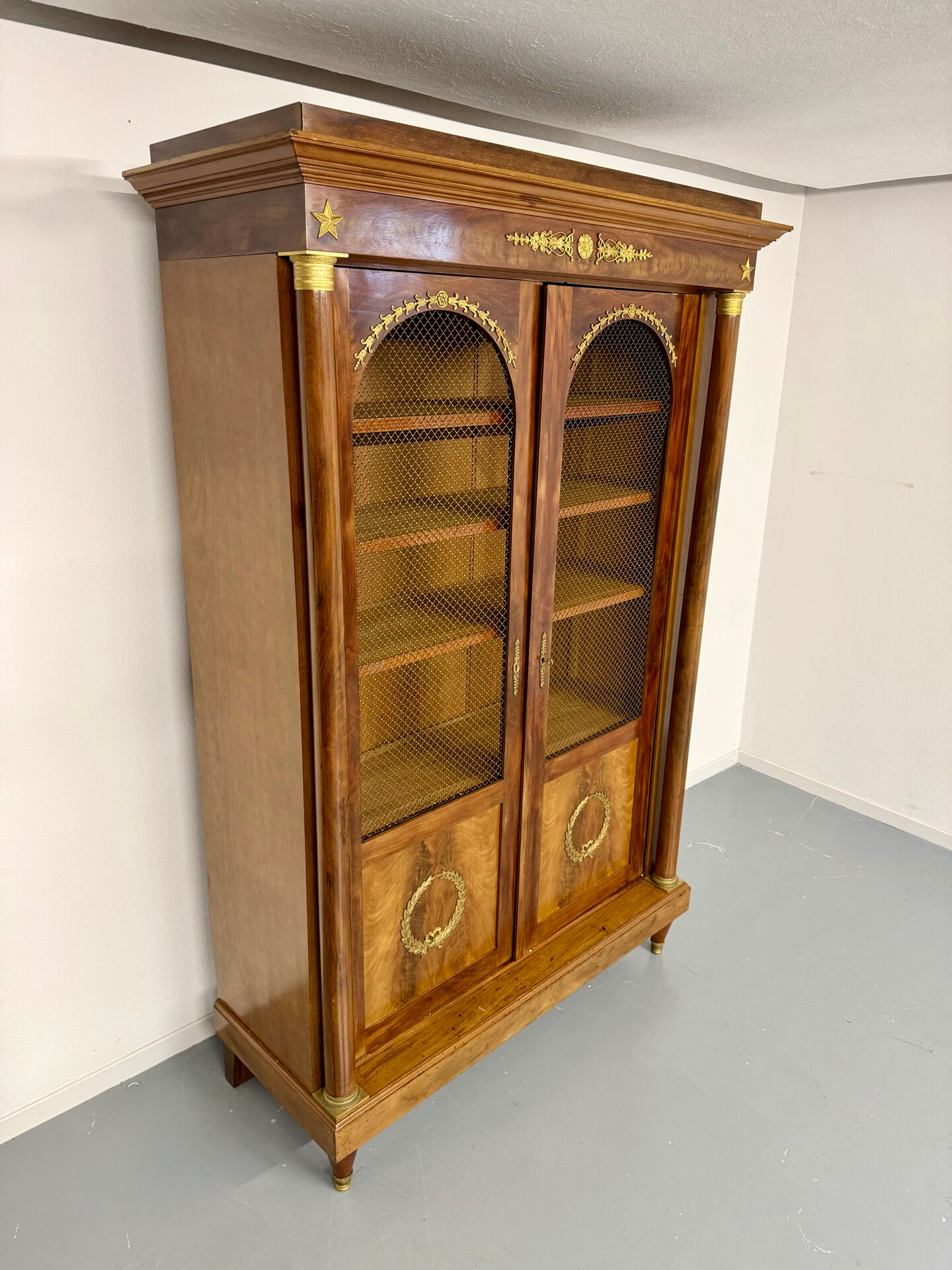 Large Empire-style library in wood with gilded bronze ornaments.