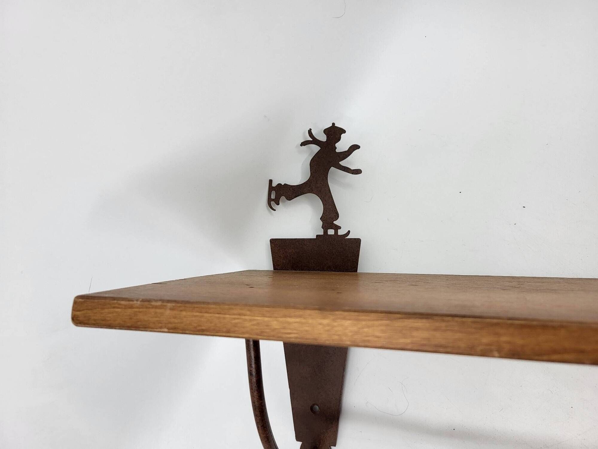 Wall shelf in wood and metal with a decoration of ice skaters.