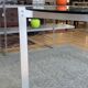 Round dining table with a glass top and brushed metal triangular frame.