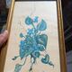 Decorative table with vintage blue flowers in a golden frame.
