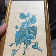 Decorative table with vintage blue flowers in a golden frame.