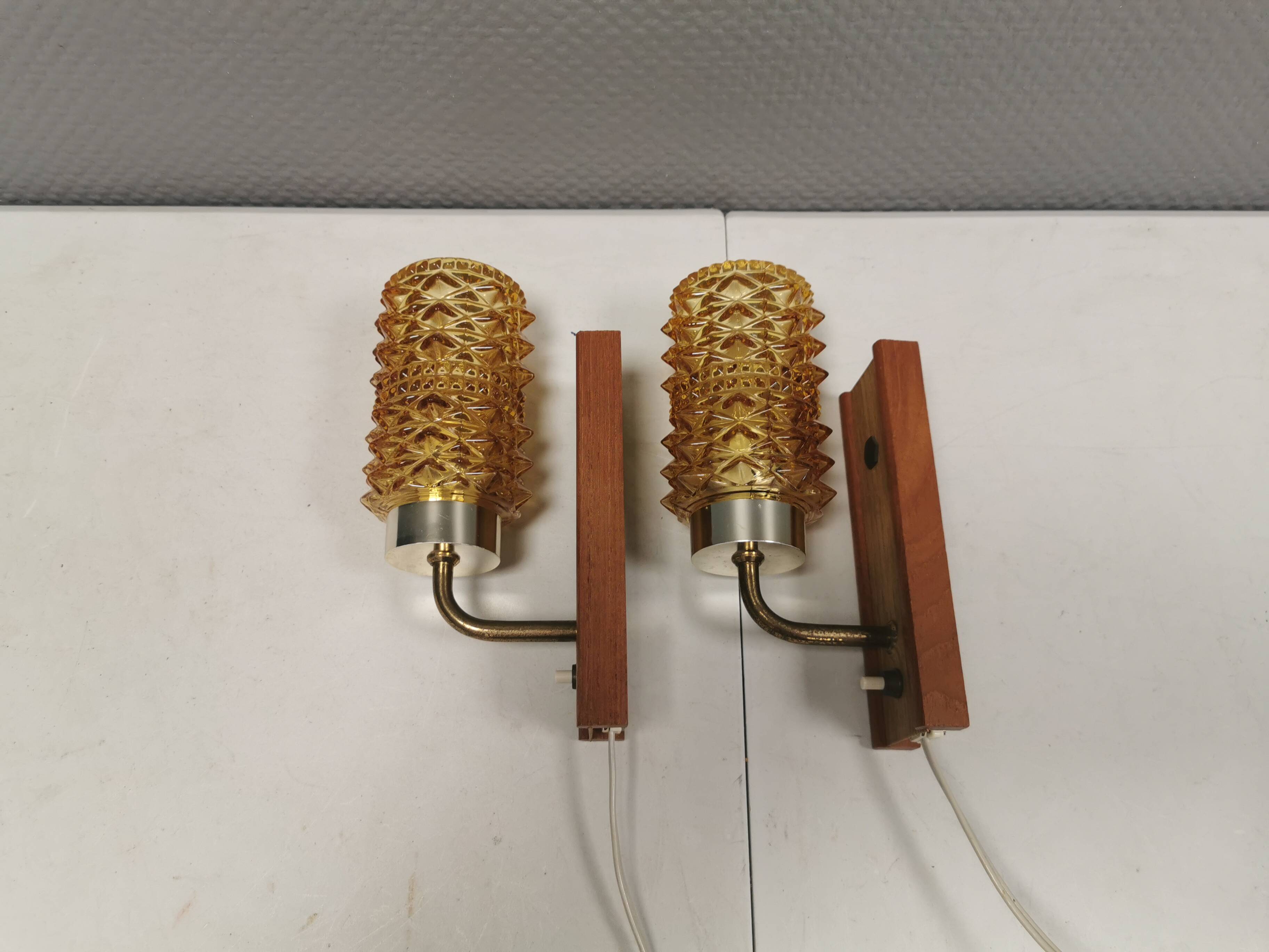 A set of wall lamps in teak wood, with amber colored glass