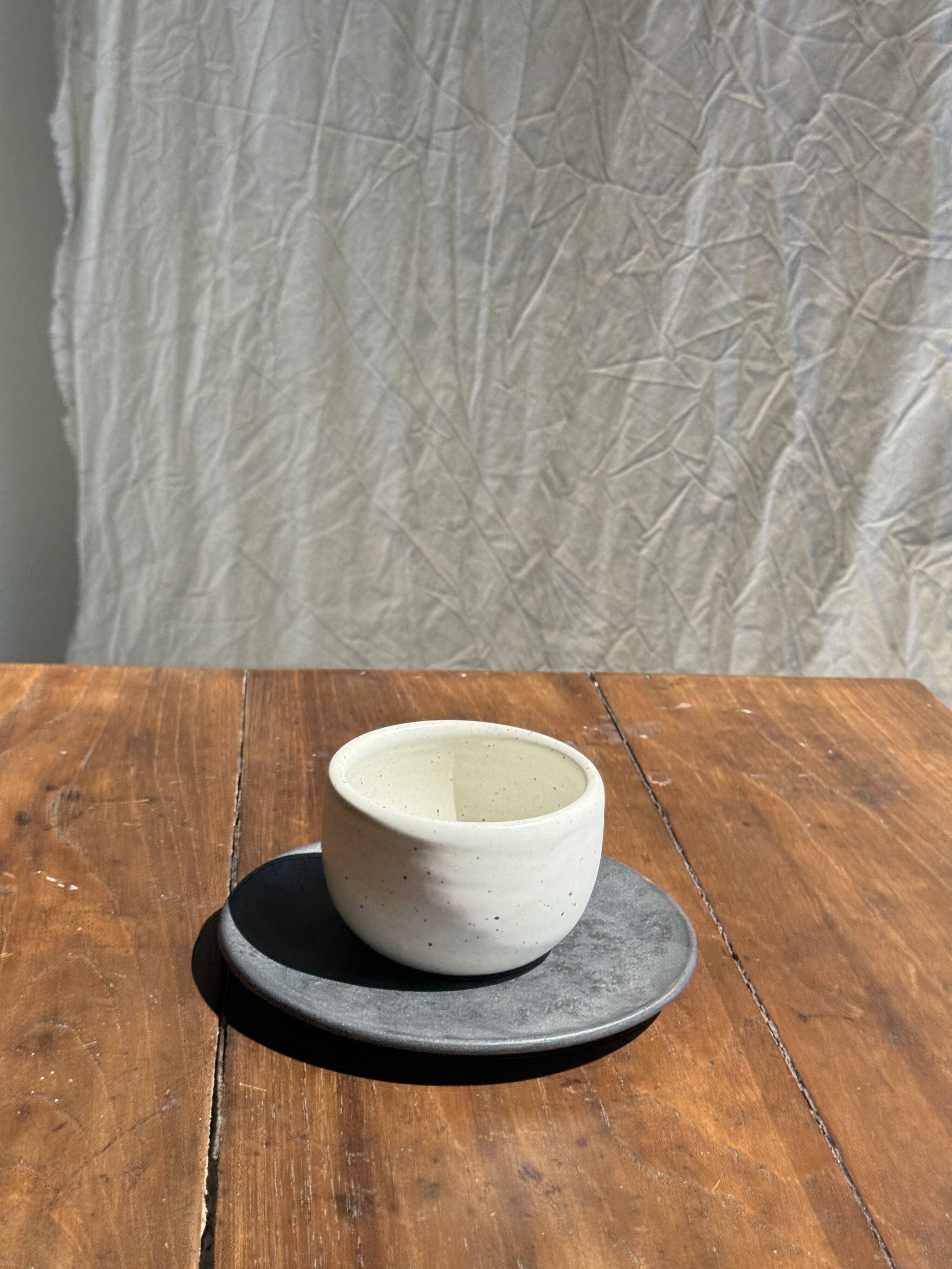 White Indonesian ceramic cup and gray saucer