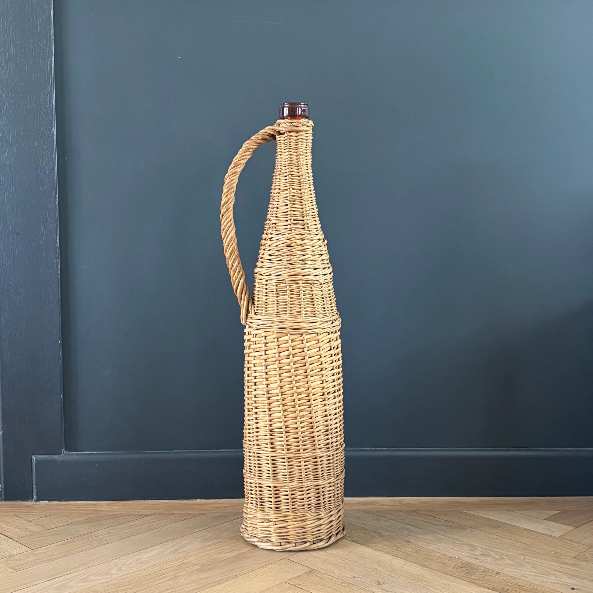 Amber glass bottle in its wicker handle basket.