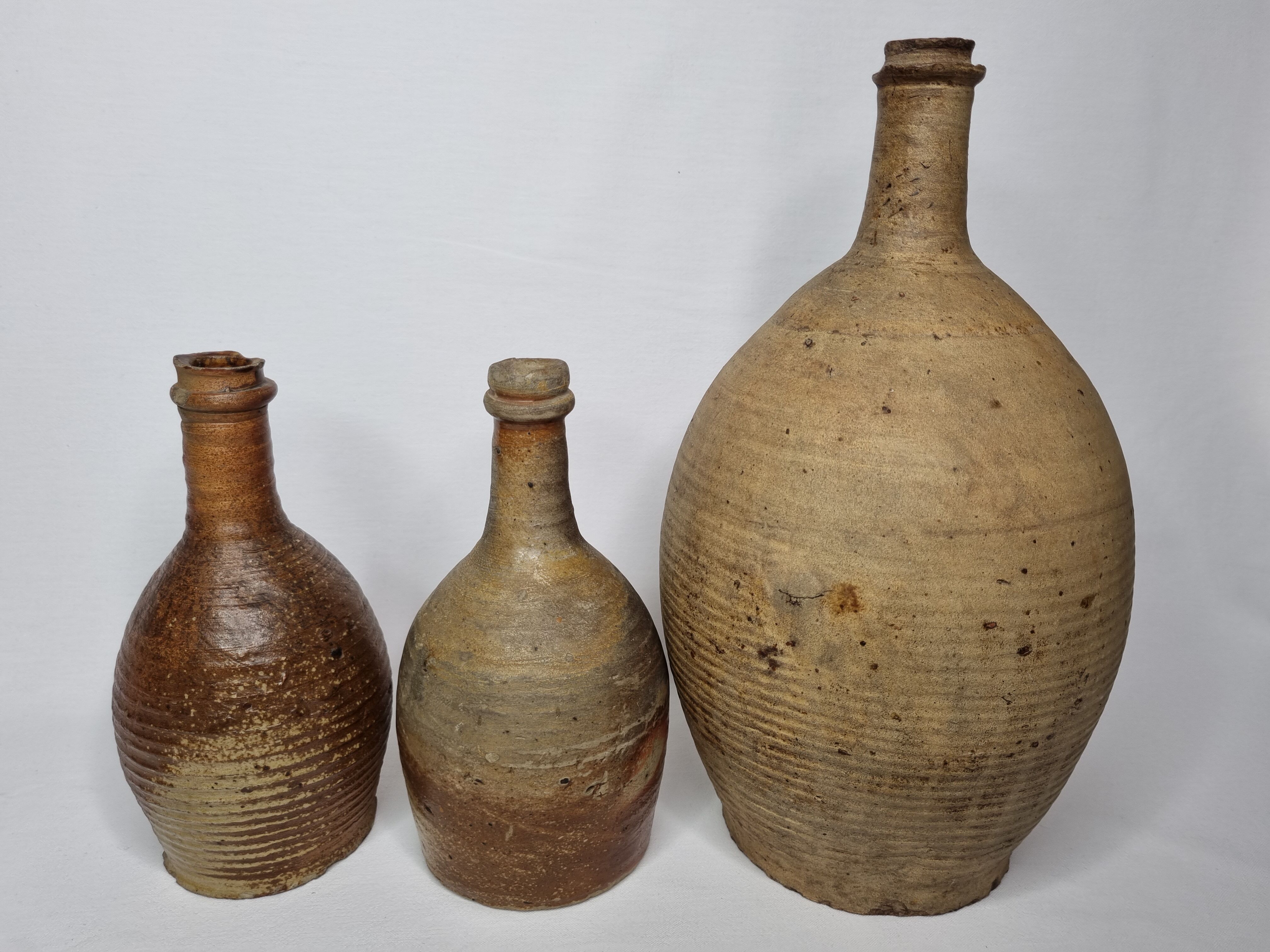 Set of three old enamelled terracotta bottles, 33 cm