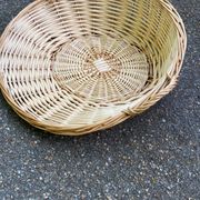 Round presentation basket made of woven wicker and rattan.