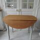 Walnut table with raised flaps, base on verdigris casters.