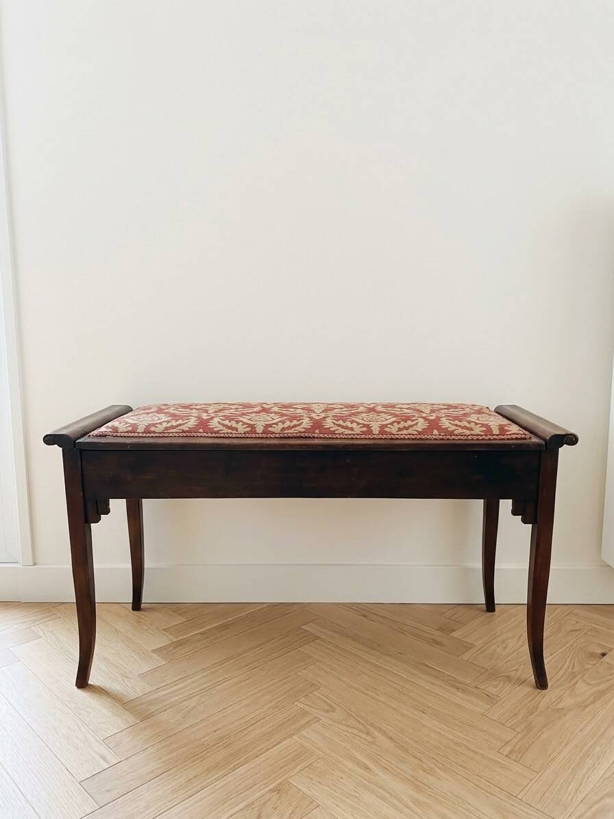 Antique wooden storage bench with red fabric.