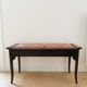 Antique wooden storage bench with red fabric.