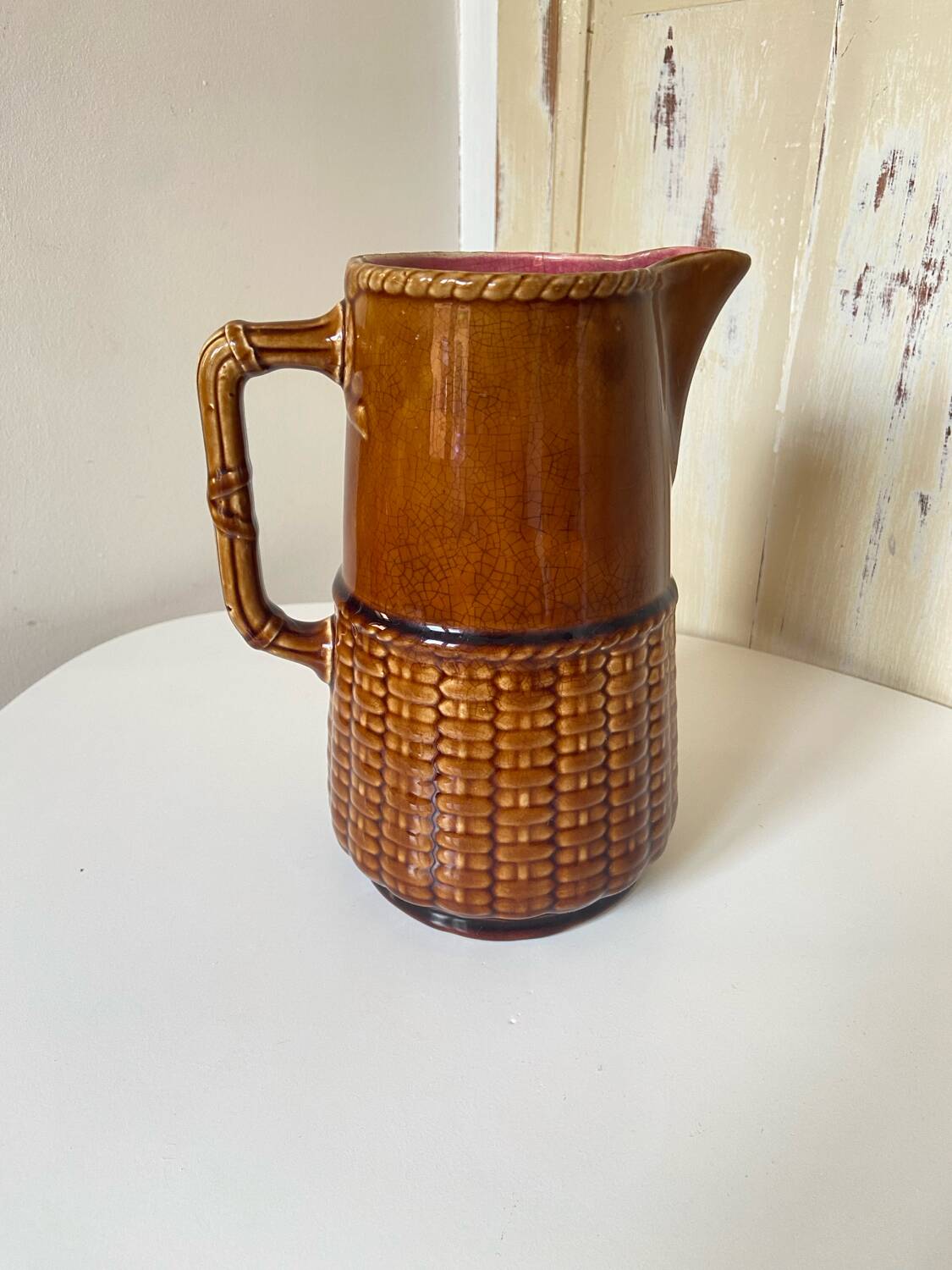Antique vintage ceramic pitcher or jug from Sarreguemines, France. Brown with a pink interior, imitation basket.