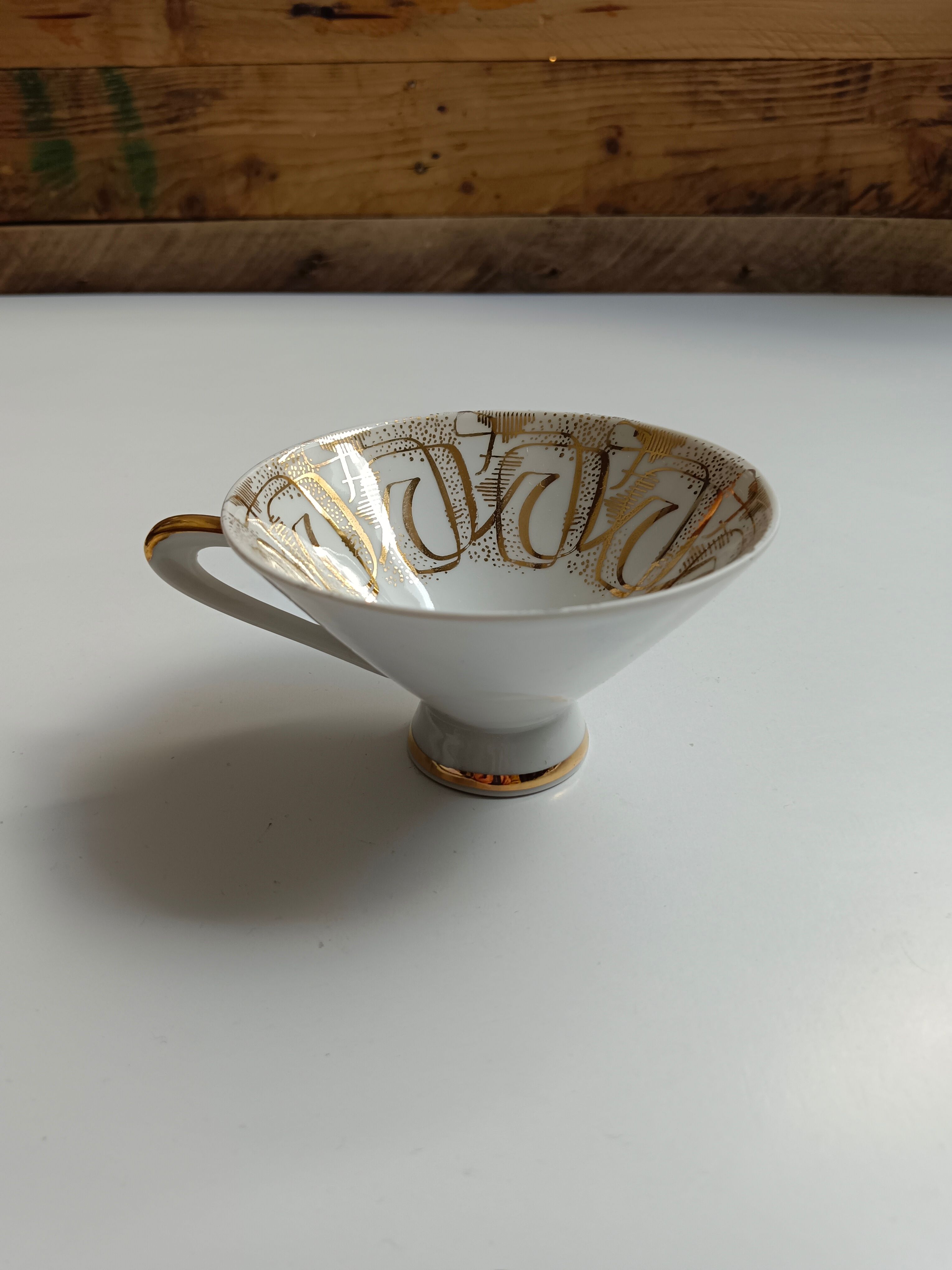 Solitaire tea cup, saucer, and dessert plate in white and gold.