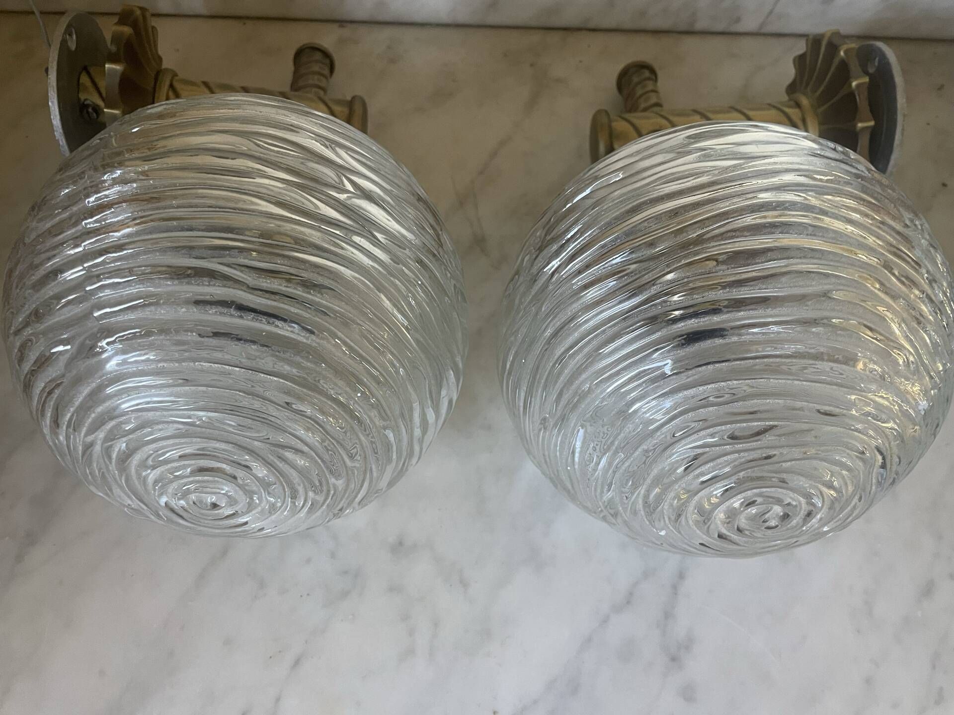 Pair of neoclassical wall sconces in twisted brass and ribbed glass.
