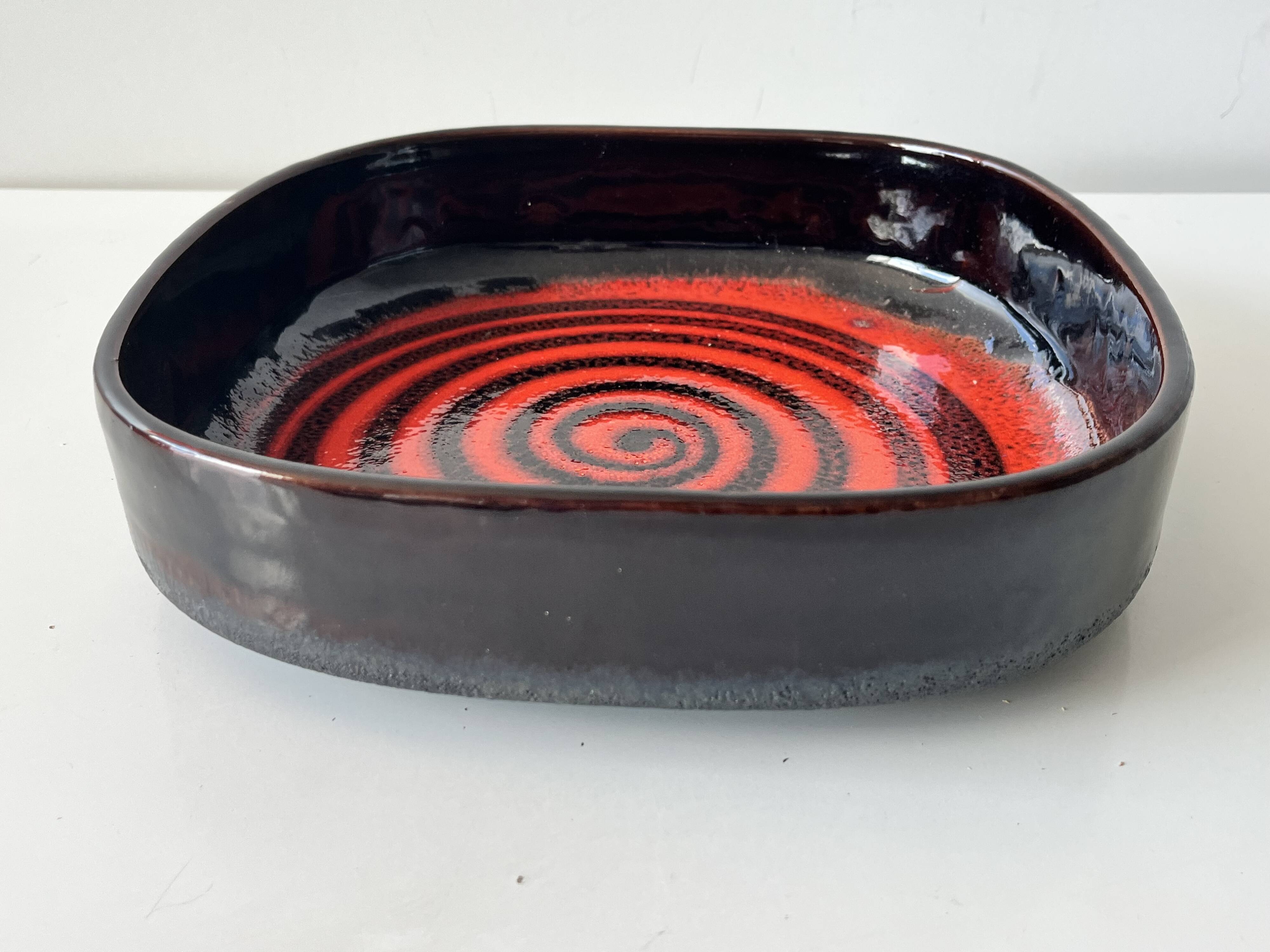 Large decorative ceramic catchall with red and black spiral pattern.