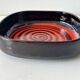 Large decorative ceramic catchall with red and black spiral pattern.