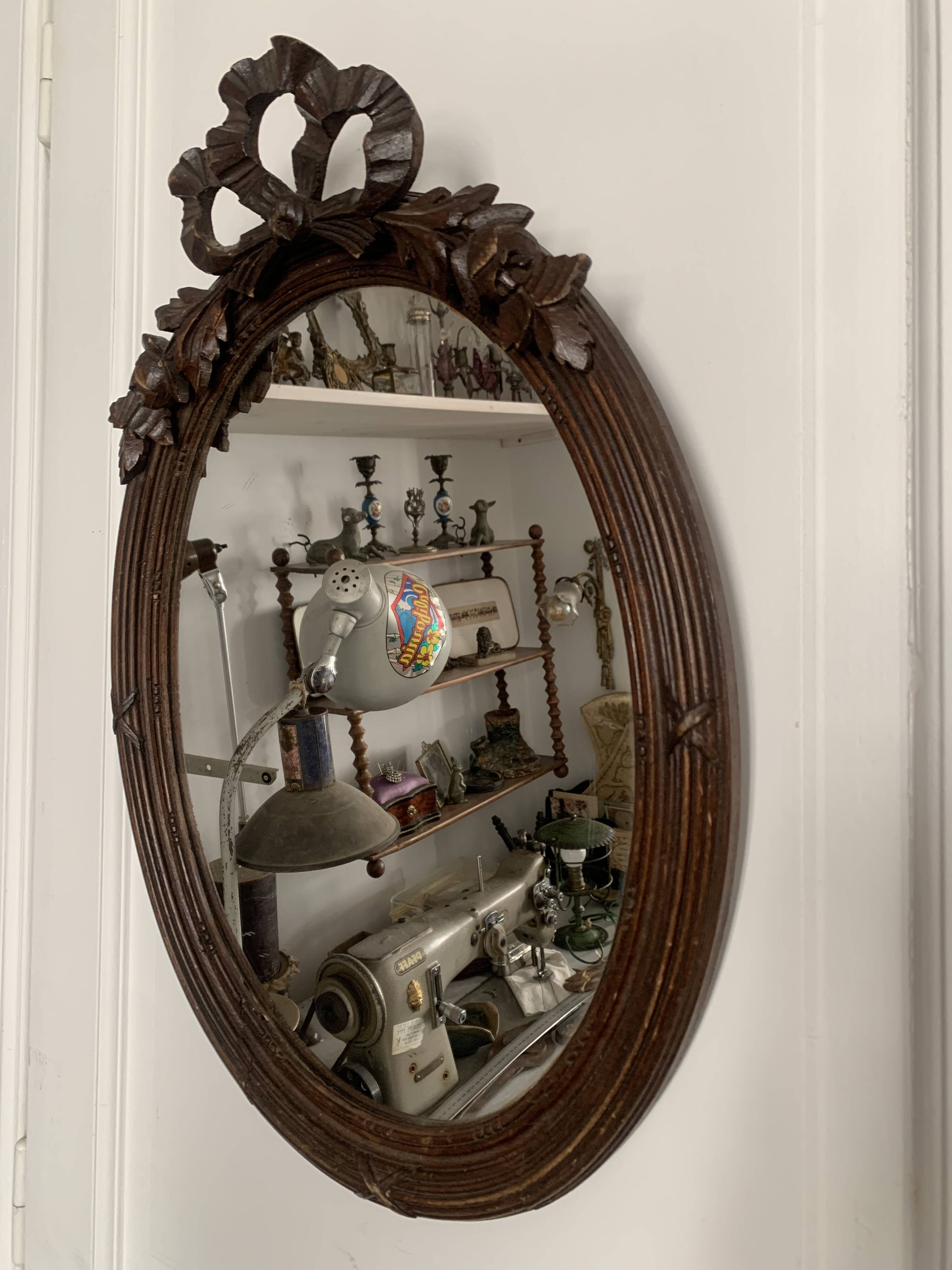 Antique oval mirror in carved wood and Louis XVI style knot