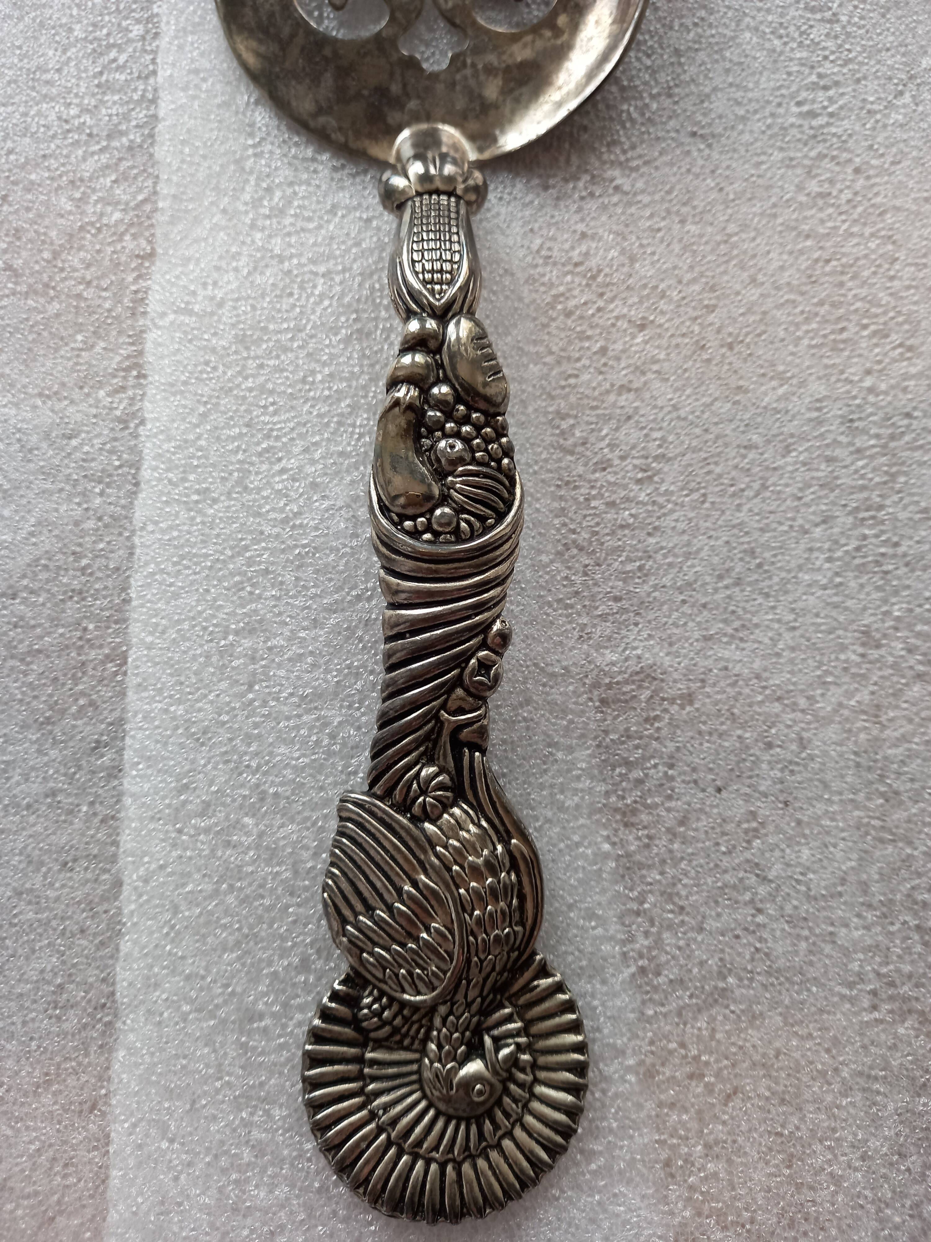 Vintage serving spoon with a carved relief handle.