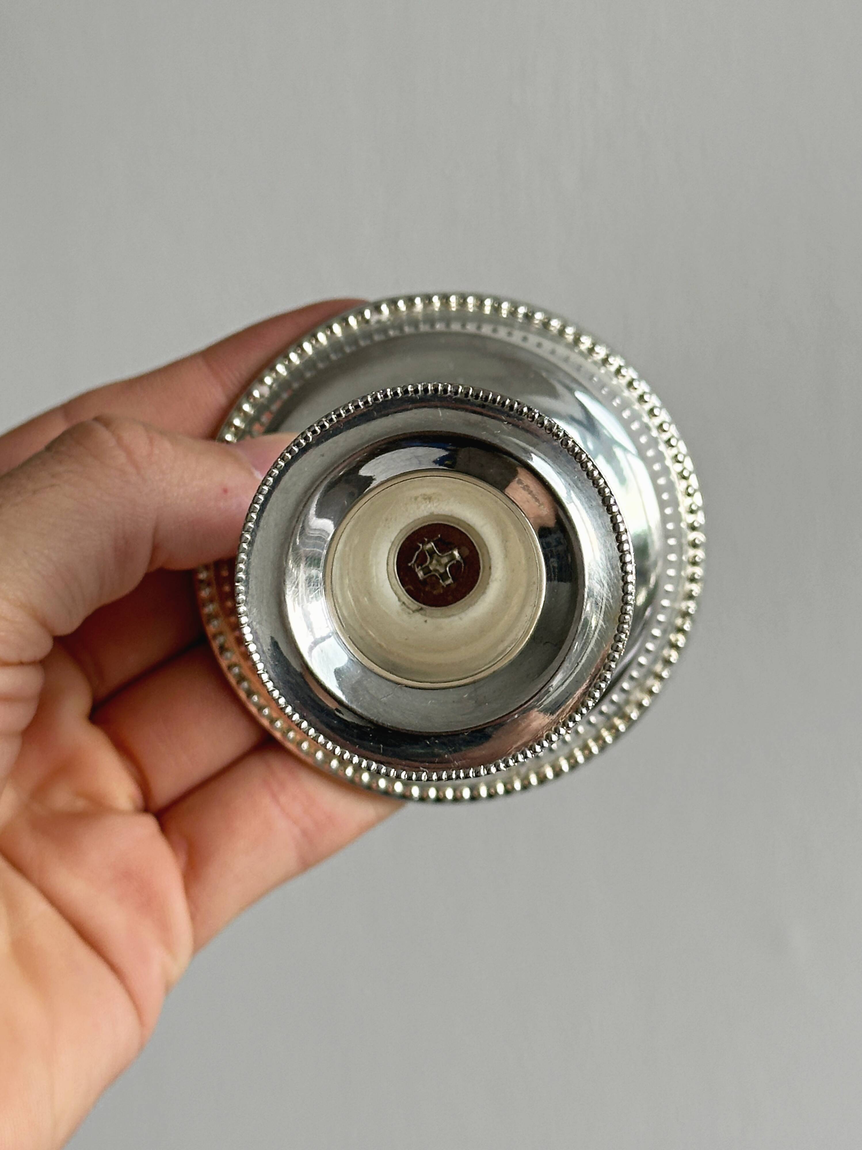 A pair of small silver-white metal candle holders.