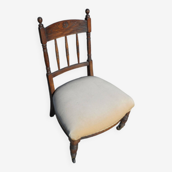 Old low nursery chair in carved wood