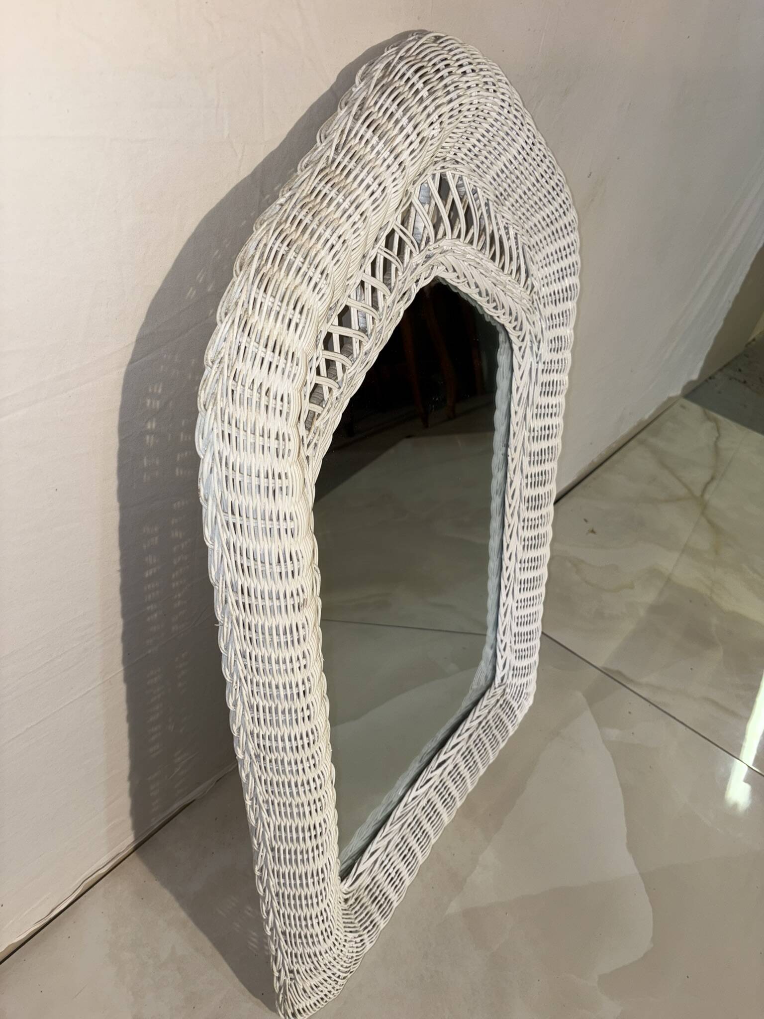 Vintage white rattan mirror with a gothic frame.