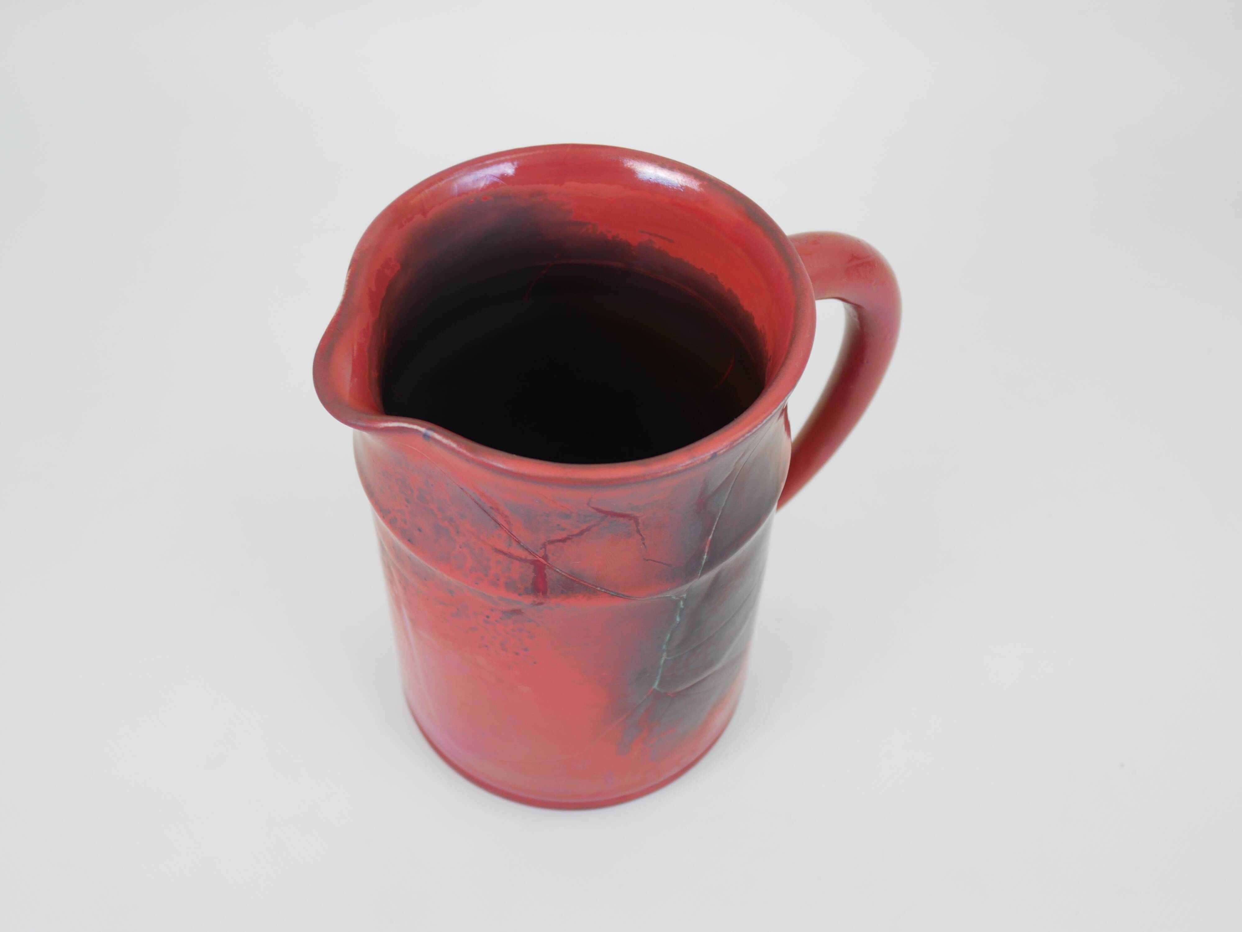 Red glazed ceramic jug with relief