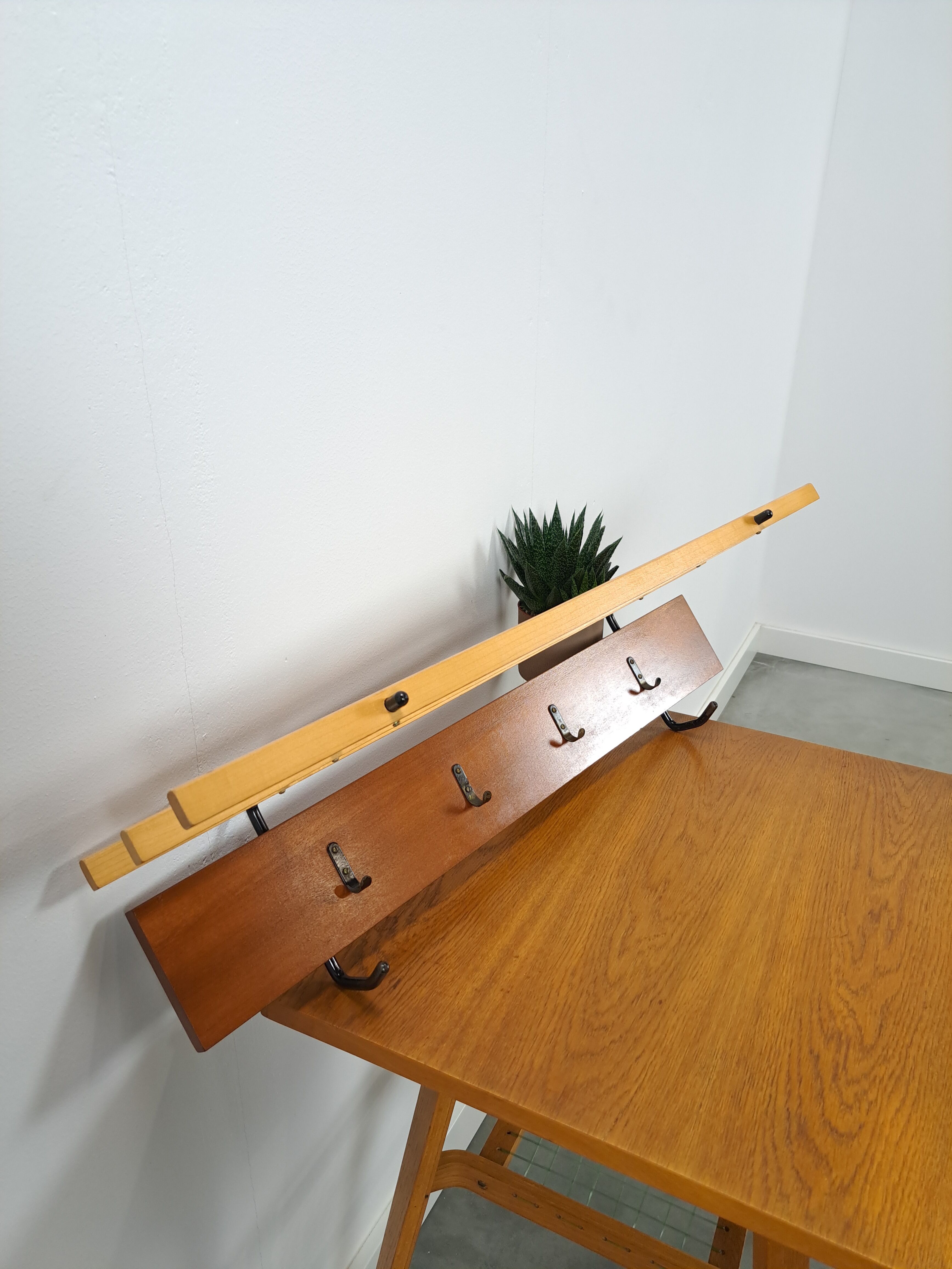Vintage wall coat rack with black hooks and light wood