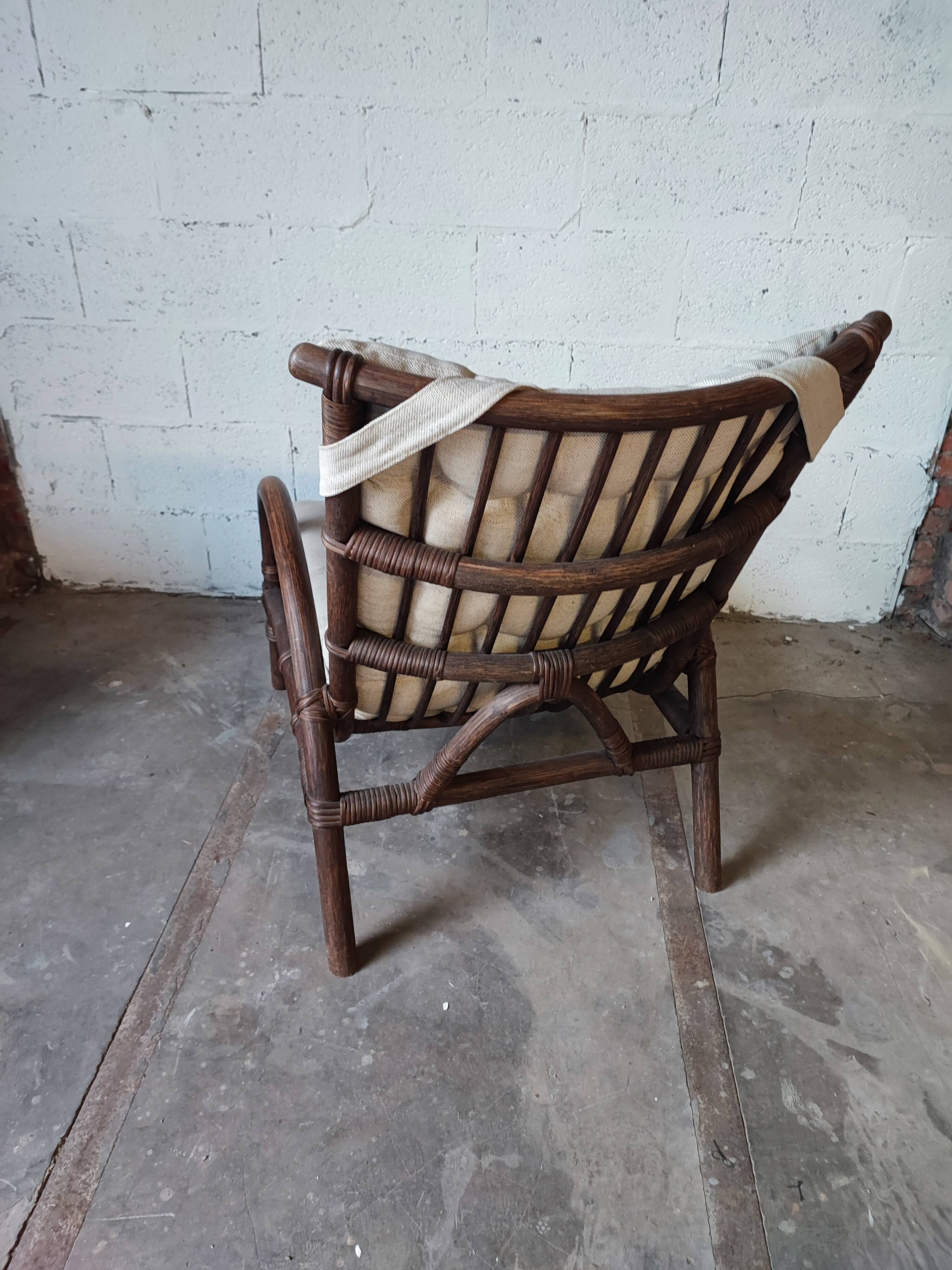 Relaxed armchair in bamboo and rattan with its small side table. Beige linen cushion.