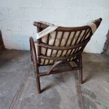 Relaxed armchair in bamboo and rattan with its small side table. Beige linen cushion.