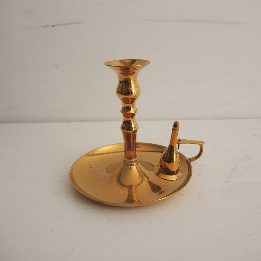 Old candlestick with brass extinguisher.